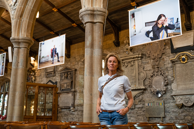 Photographer Kate Abbey stands in the Bradford Cathedral nave in front of some of her photos.